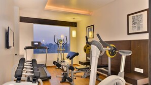 A gym with various exercise equipment, a treadmill, and a large window with a view. - Ginger Vadodara,Alkapuri (Vadodara)