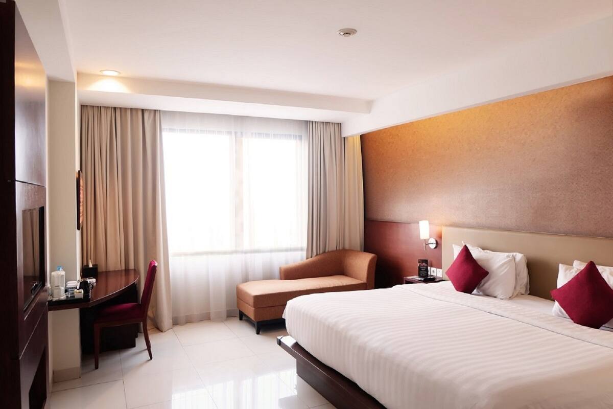 A hotel room with a bed, a desk, a chair, and a TV.