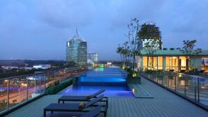 Zona de piscina en la azotea con sillones y vistas a edificios de la ciudad.