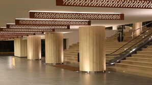 Un interior moderno con una escalera, columnas cilíndricas imponentes y un techo con diseño.
