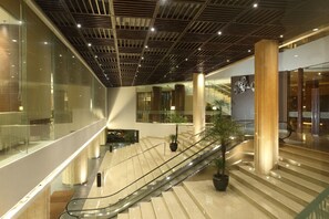 A modern interior with an escalator, glass walls, and a ceiling with a grid pattern. - Hotel Santika Premiere Bintaro (South Tangerang)