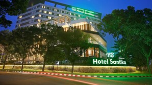 Un hotel de varios pisos con un letrero visible que dice "Hotel Santika".