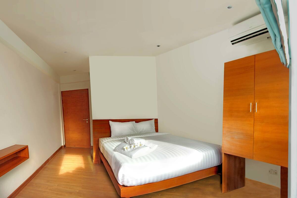 A hotel room with a wooden bed, a wardrobe, a desk, and a television.