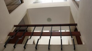 Una escalera con barandilla de madera y balaustradas de metal, que conduce a un rellano con tragaluz.