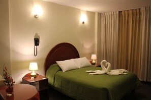 A hotel room with a green bed, two bedside lamps, a telephone, and a vase with flowers. - La Almohada del Rey (Arequipa)