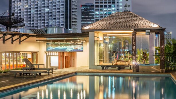 A modern hotel with a swimming pool, a lounge area, and a glass-enclosed exercise room. - The Grand Sathorn (Bangkok)