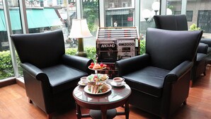 A room with two black leather chairs, a small round table with a glass top, and a box of GM2000 brand cigarettes. - The Grand Sathorn (Bangkok)