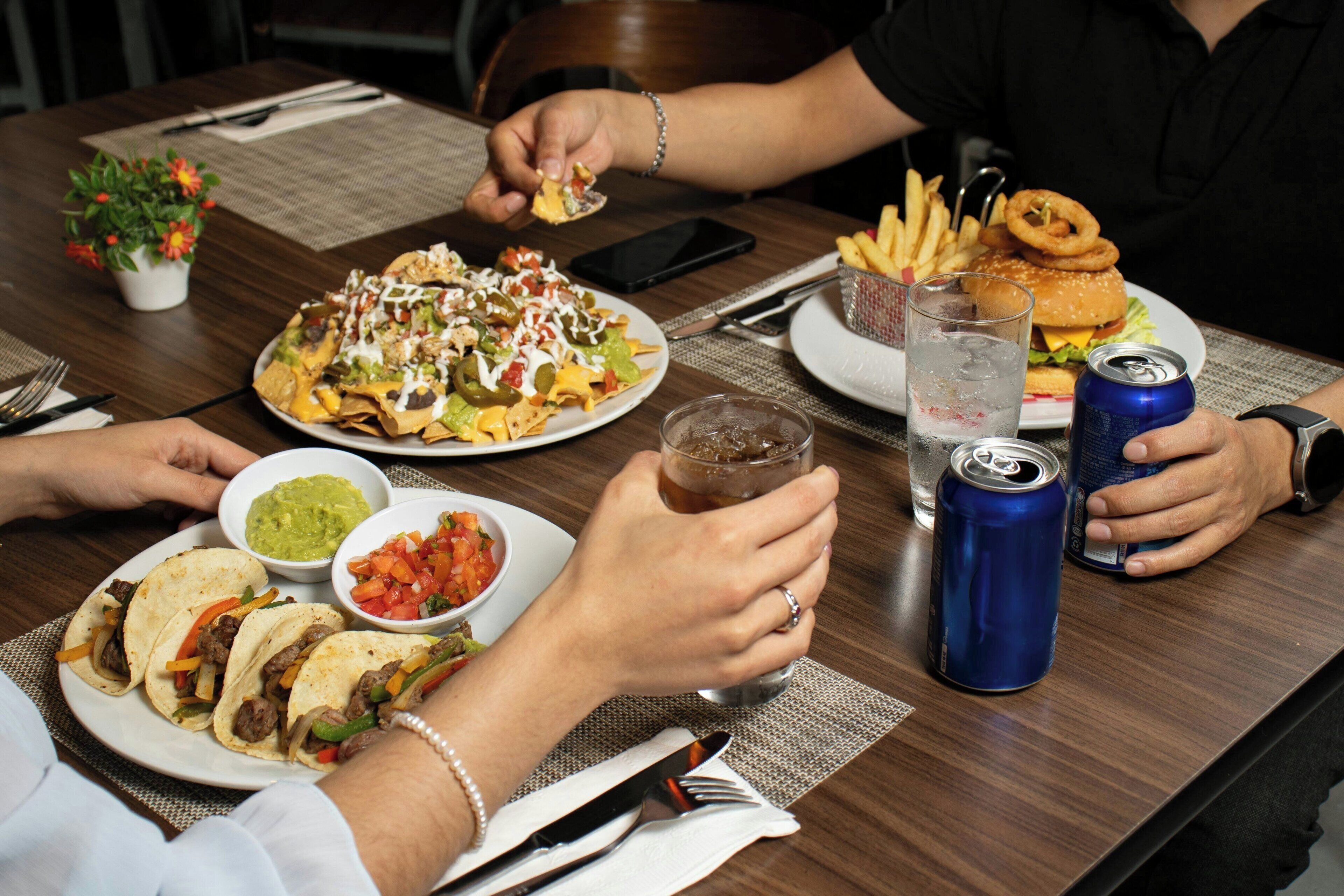 A dining table with food, drinks, and utensils.