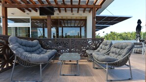 A patio with two cushioned chairs and a small table, wooden beams, and a TV mounted on the wall. - Four Points by Sheraton Cancun Centro (Cancun)
