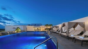A rooftop pool area with lounge chairs and umbrellas, a clear sky, and a view of the cityscape. - Four Points by Sheraton Cancun Centro (Cancun)