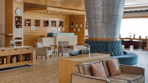 A spacious lobby with a large mosaic column, comfortable seating, and a wooden reception desk. - Four Points by Sheraton Cancun Centro (Cancun)