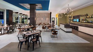 A modern restaurant with multiple dining tables and chairs, a bar area with shelves, and a large chandelier. - Four Points by Sheraton Cancun Centro (Cancun)
