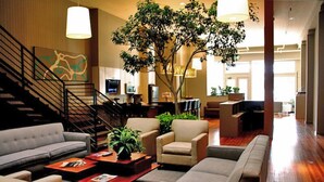 A spacious lobby with a staircase, seating area, and a large tree. - The Inn on Whitworth (Brookhaven)