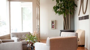 A modern living room with a sofa, armchairs, a coffee table, and a potted plant. - The Inn on Whitworth (Brookhaven)