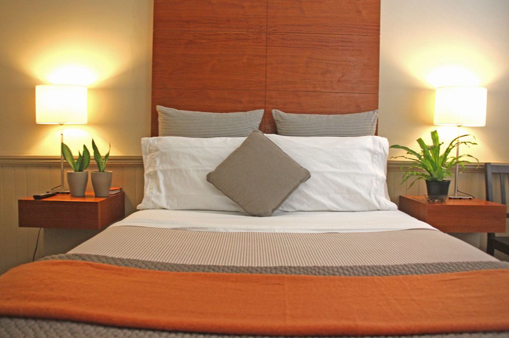 A hotel room with a large bed, two bedside tables with lamps, and potted plants.