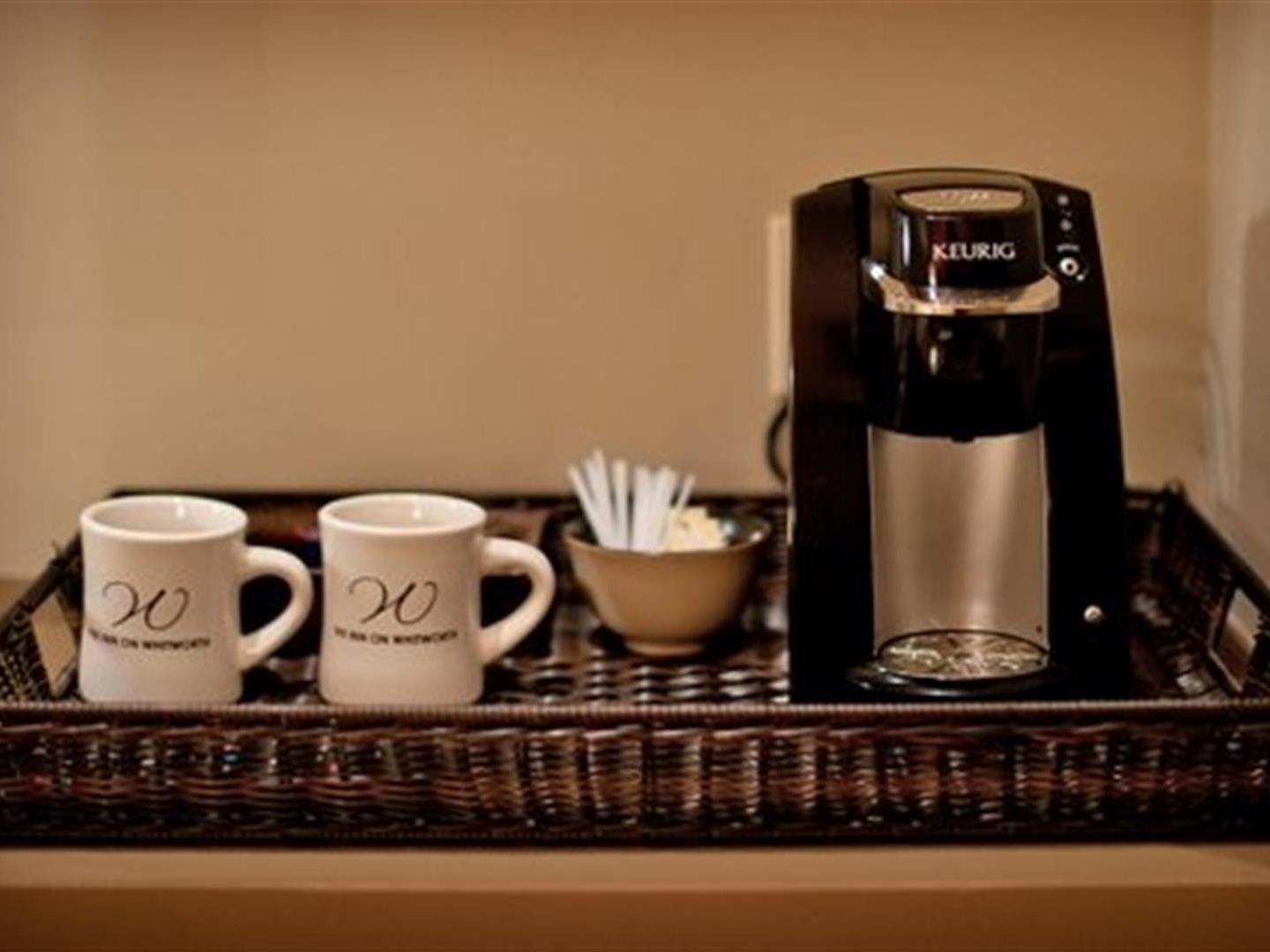 A coffee maker and two mugs on a tray.