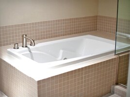 Un baño moderno con una bañera rectangular, un solo grifo y un box de ducha de vidrio.