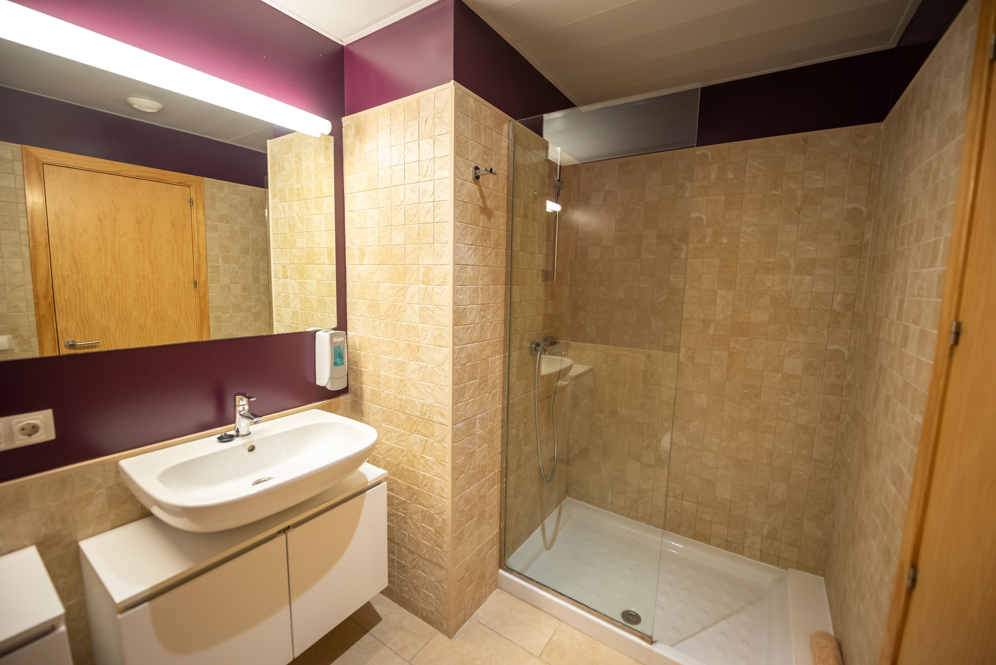 A modern bathroom with a glass-enclosed shower, a white sink, and a wooden cabinet.