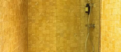 A bathroom with a glass-enclosed shower, a toilet, and a sink.