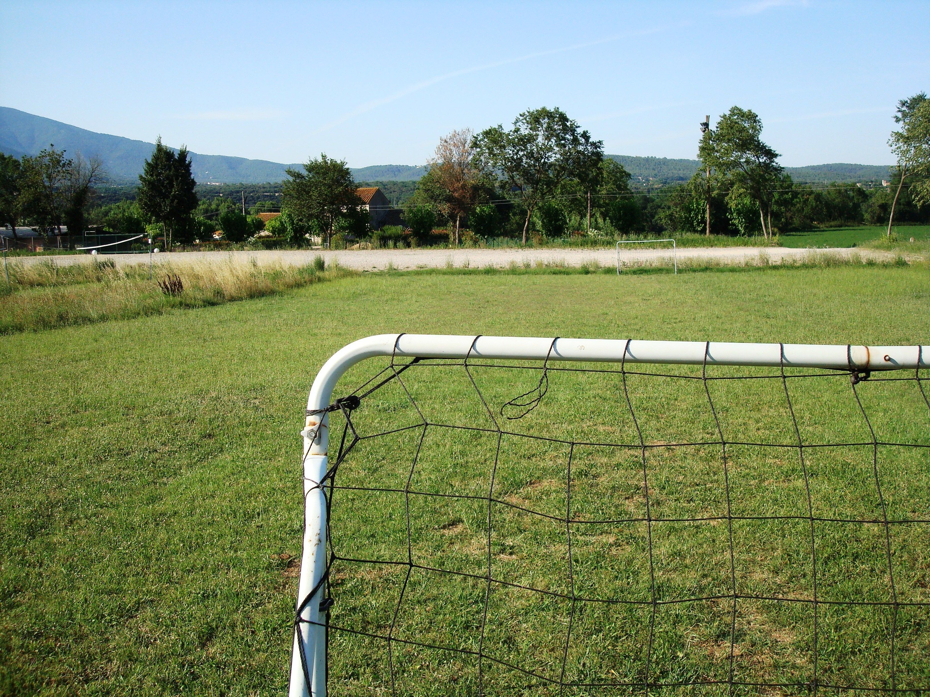 A soccer goal in a grassy field with a clear sky and distant mountains.