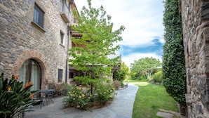 A stone building with a stone pathway, outdoor seating, and a well-maintained garden. - L'Arcada de Fares (Sant Ferriol)