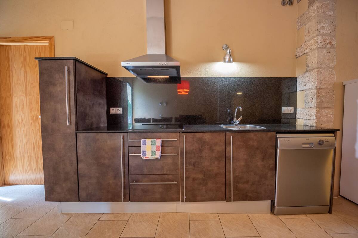 A kitchen with a built-in dishwasher, a stainless steel range hood, and a granite countertop.