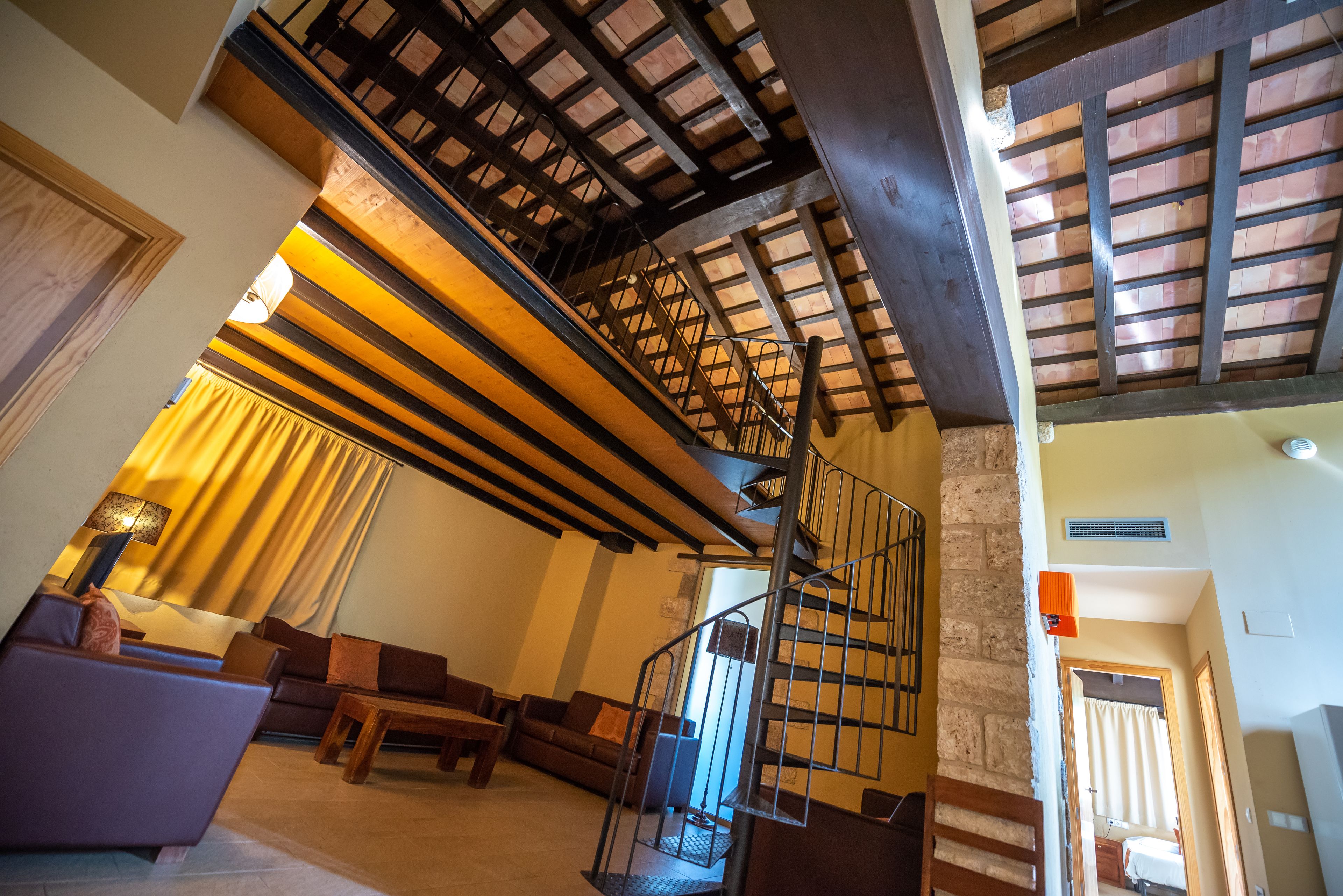 A spacious living area with a high ceiling, a staircase, and a cozy seating arrangement.