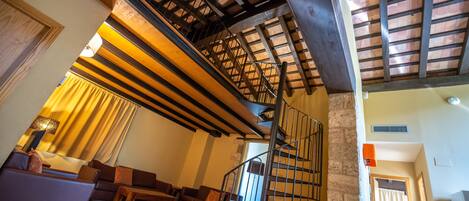 A spacious living area with a high ceiling, a staircase, and a cozy seating arrangement.