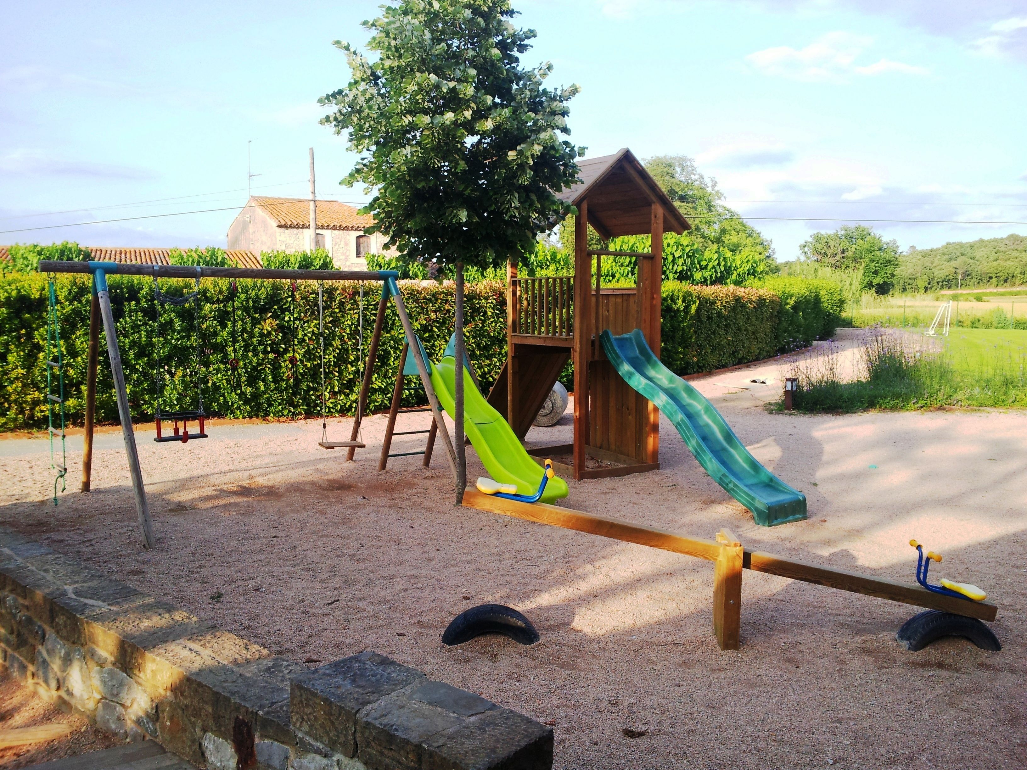 A playground with swings, a slide, and a seesaw.