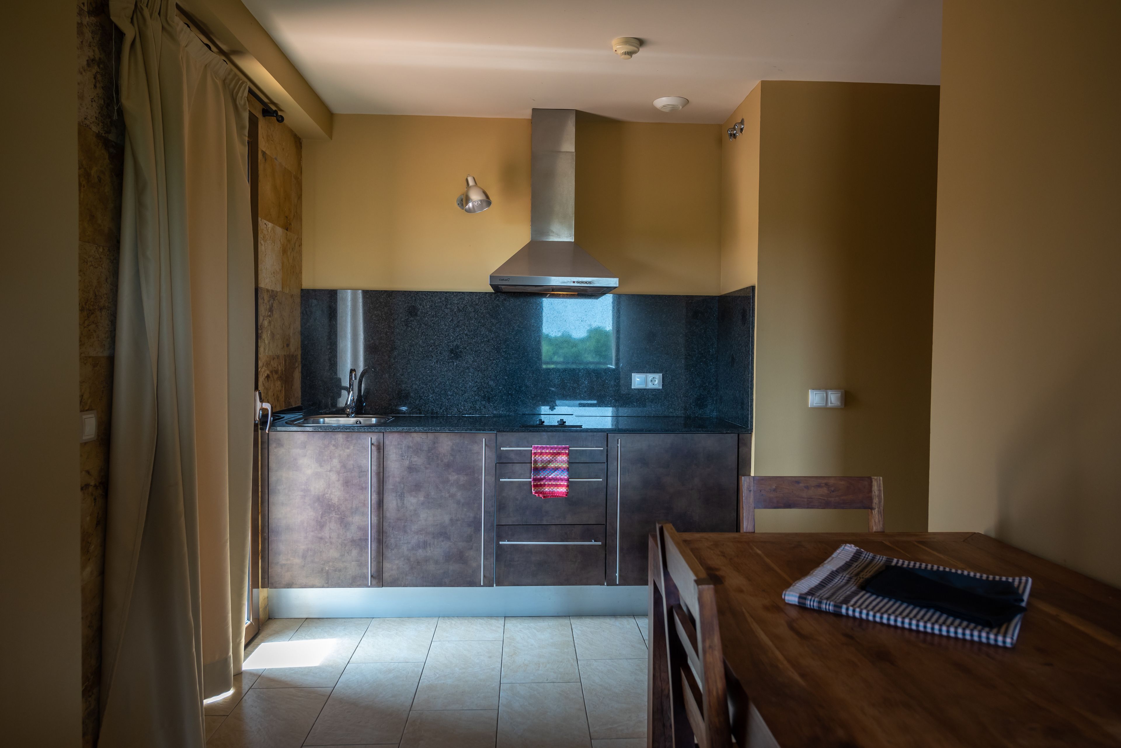 Una cocina moderna con extractor de acero inoxidable, horno empotrado y encimera de granito oscuro.
