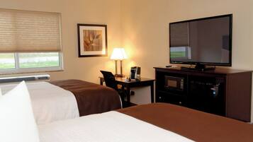 A hotel room with two beds, a desk with a lamp, a television, and a microwave.