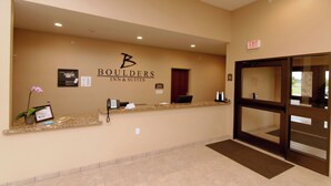 A reception area with a reception desk, a plant, and a sign for Boulders Inn & Suites. - Cobblestone Inn & Suites - Fort Madison (Fort Madison)