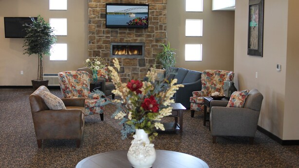 A lobby with a stone fireplace, comfortable seating, and a flat-screen TV mounted on the wall. - Cobblestone Inn & Suites - Fort Madison (Fort Madison)