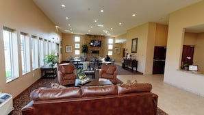 A spacious lobby with a leather sofa, dining area, and a TV mounted on a stone wall. - Cobblestone Inn & Suites - Fort Madison (Fort Madison)