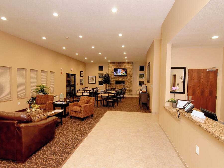 Un hall de hotel con mostrador de recepción, zona de estar y un televisor montado en la pared.