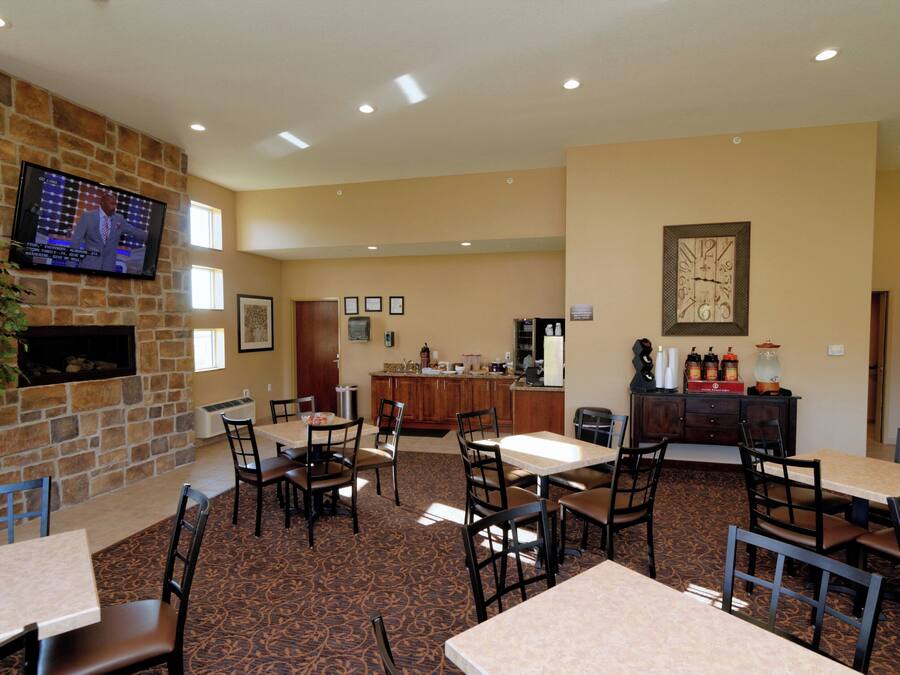 Un hall de hotel con pared de piedra, televisor de pantalla plana, chimenea y zona de bar.