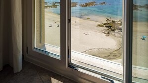 A room with a large sliding glass door leading to a beach view. - Hotel El Puente (Sanxenxo)