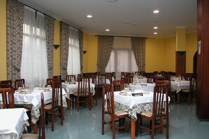 Un comedor con varias mesas y sillas dispuestas en filas.
