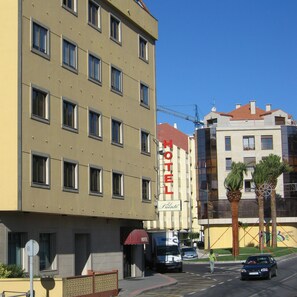 Un hotel de varios pisos con un letrero grande que dice 'HOTEL', un toldo rojo y una entrada visible.