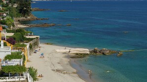 A beach with clear blue water, a sandy shore, and a few people enjoying the sun. - Hotel El Puente (Sanxenxo)