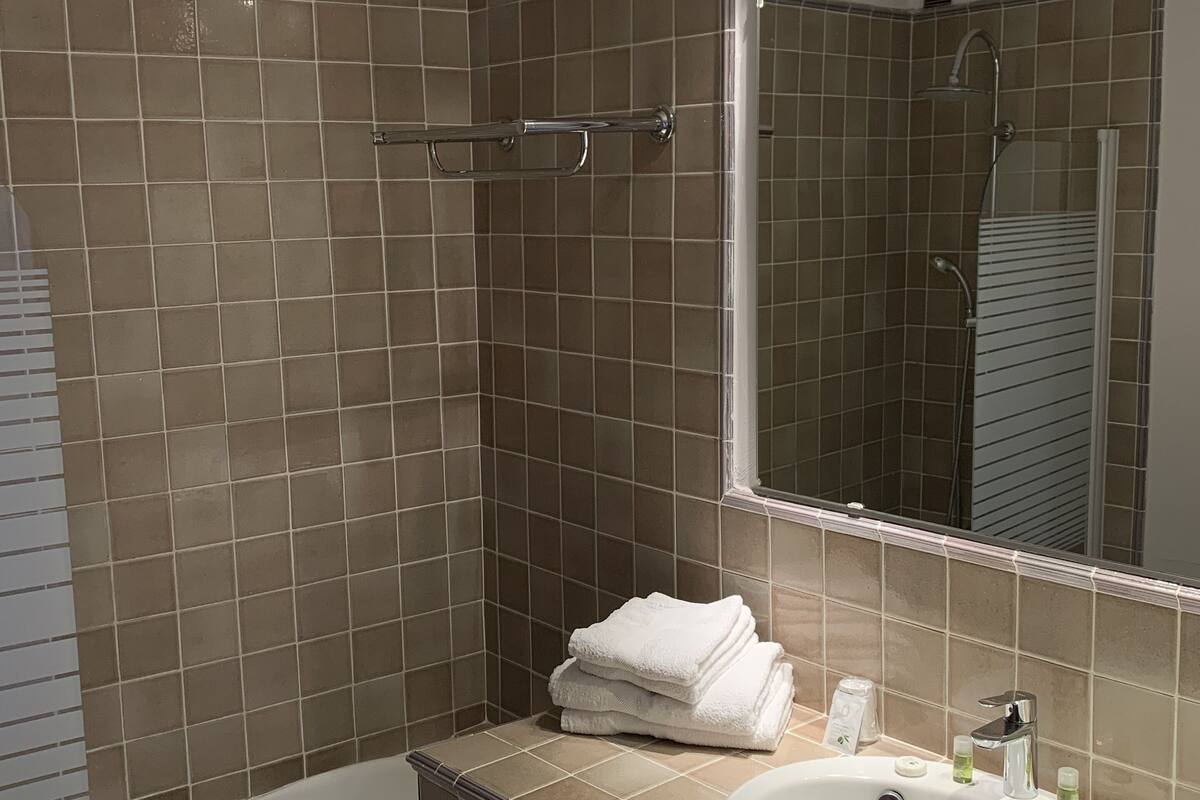 Une salle de bain avec une baignoire, un lavabo et un grand miroir.