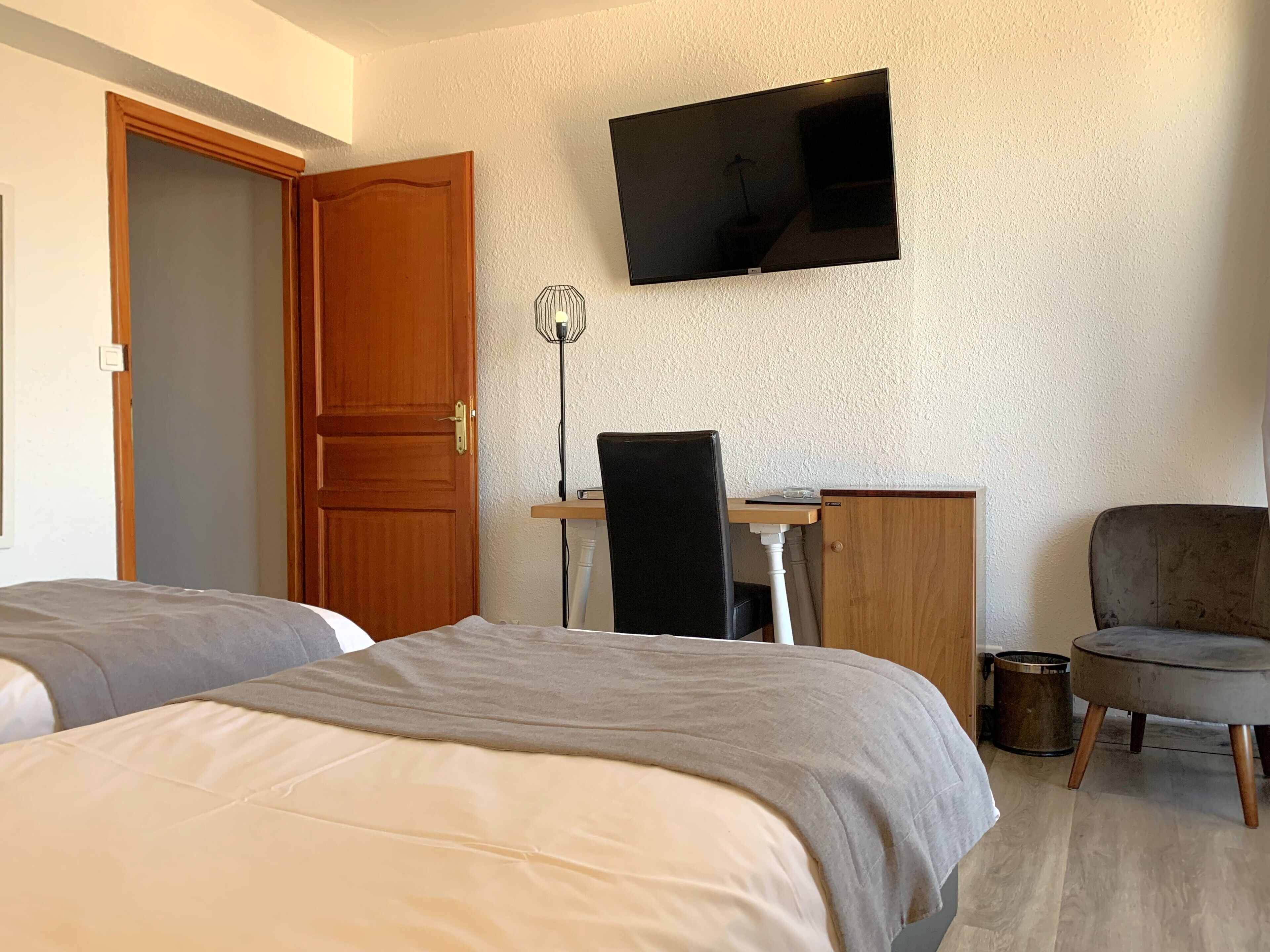 Una habitación de hotel con dos camas, un escritorio, una silla, un televisor y un cesto de basura.