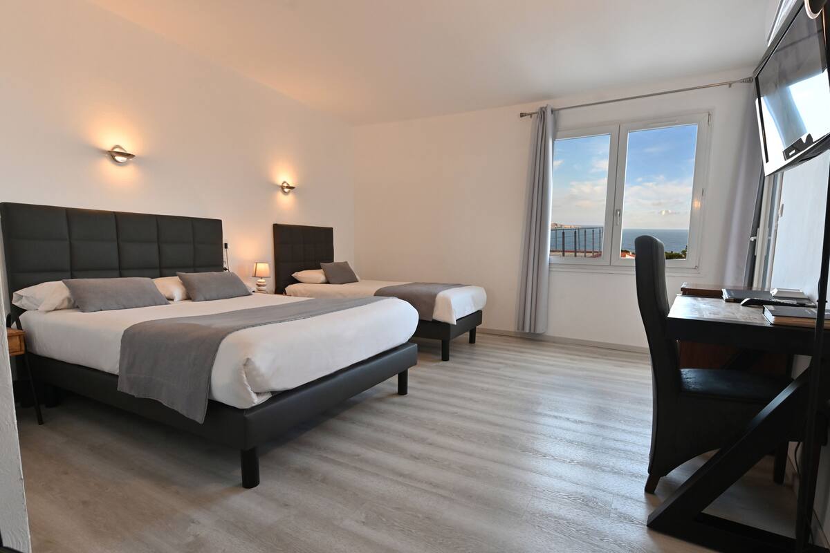 Une chambre d’hôtel moderne avec deux lits, un bureau et une vue sur la mer.