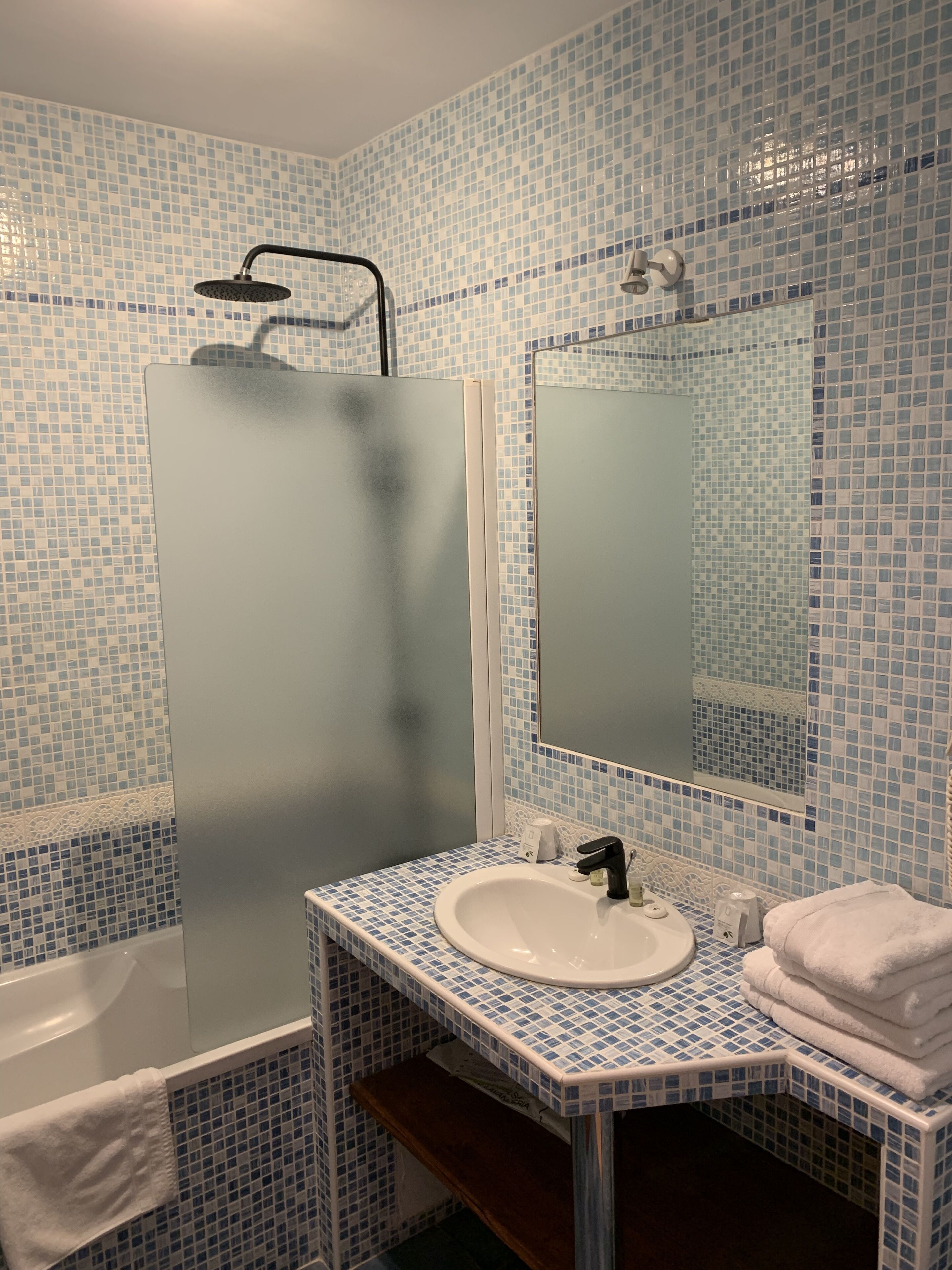A bathroom with a sink, mirror, and shower.
