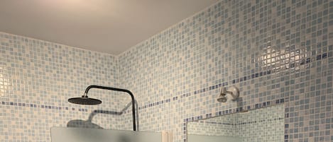 A bathroom with a sink, mirror, and shower.