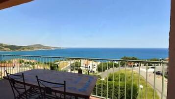 Un balcón con mesa y sillas que da a vistas de la costa.