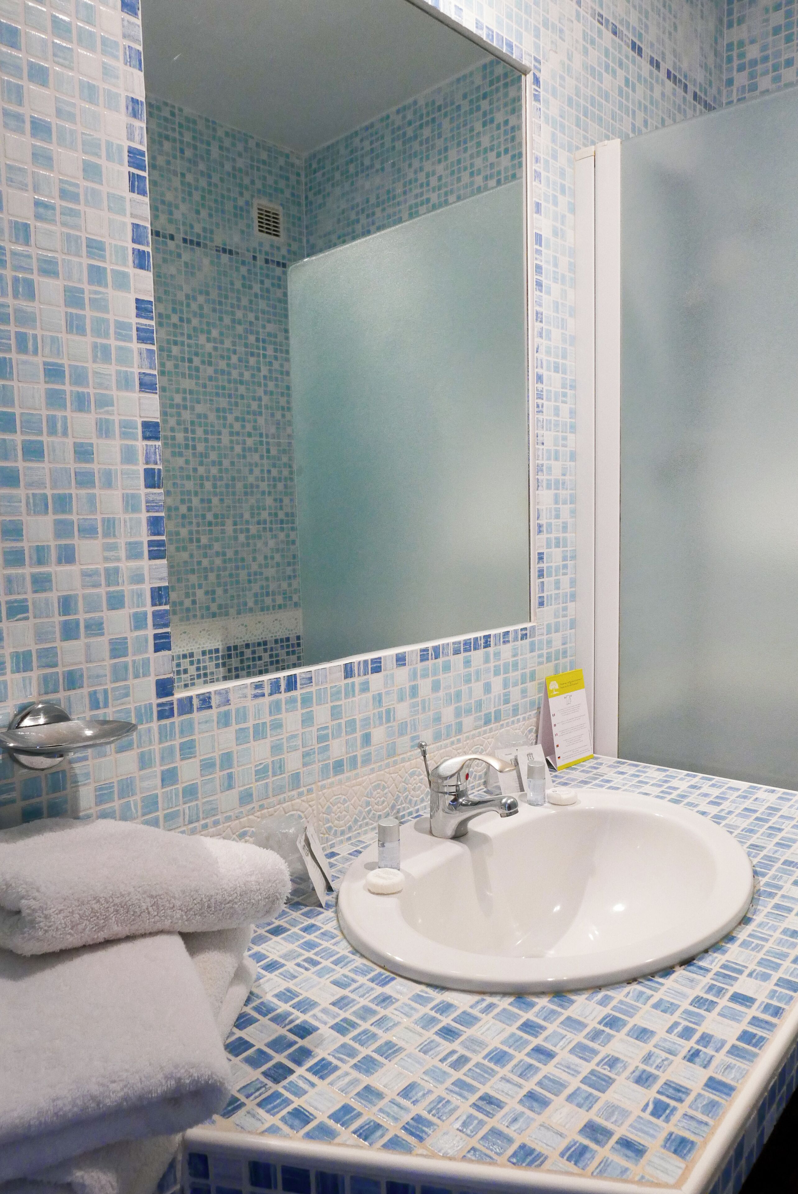 A bathroom with a sink, mirror, and tiled walls.