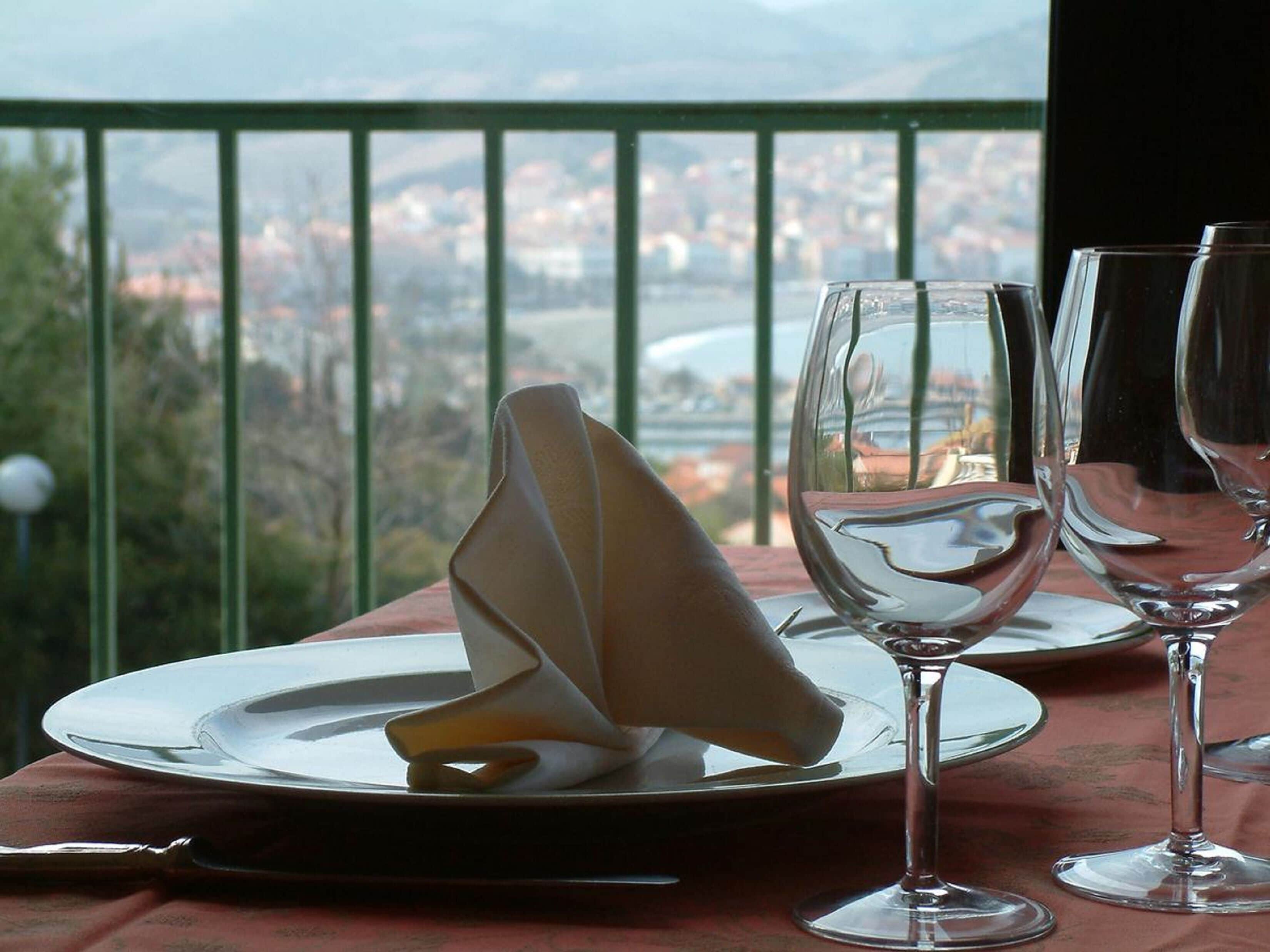 A dining table with a folded napkin, two wine glasses, and a plate set for a meal.