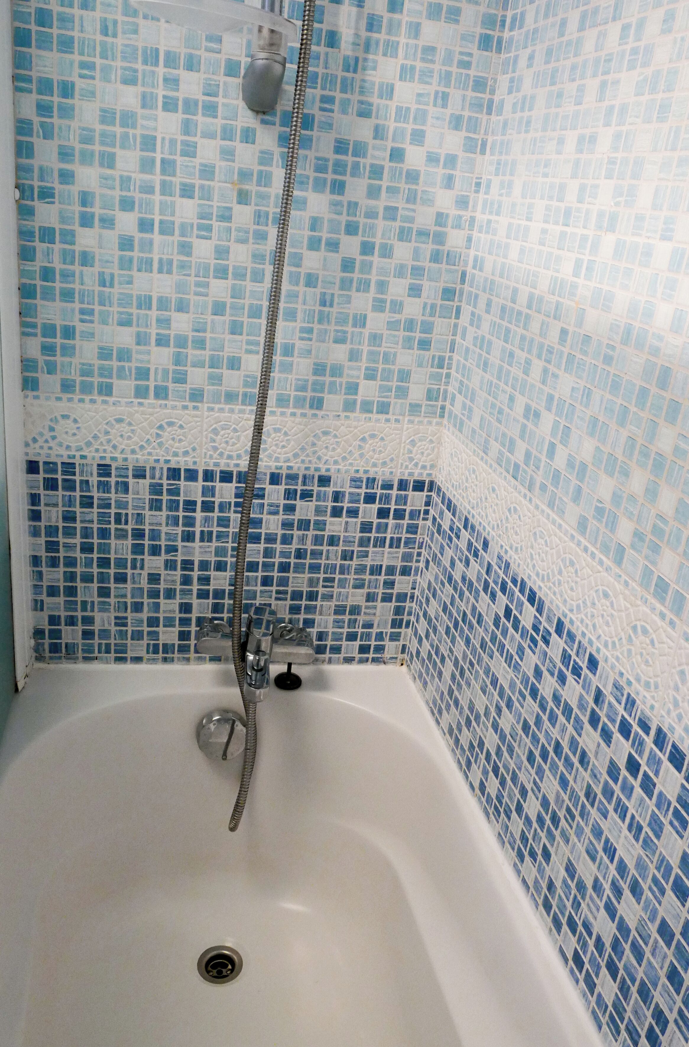 A bathroom with a bathtub, a shower head, and a drain.