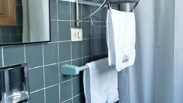 Un baño con un lavamanos azul, un espejo, un perchero con toallas y una cortina de ducha.